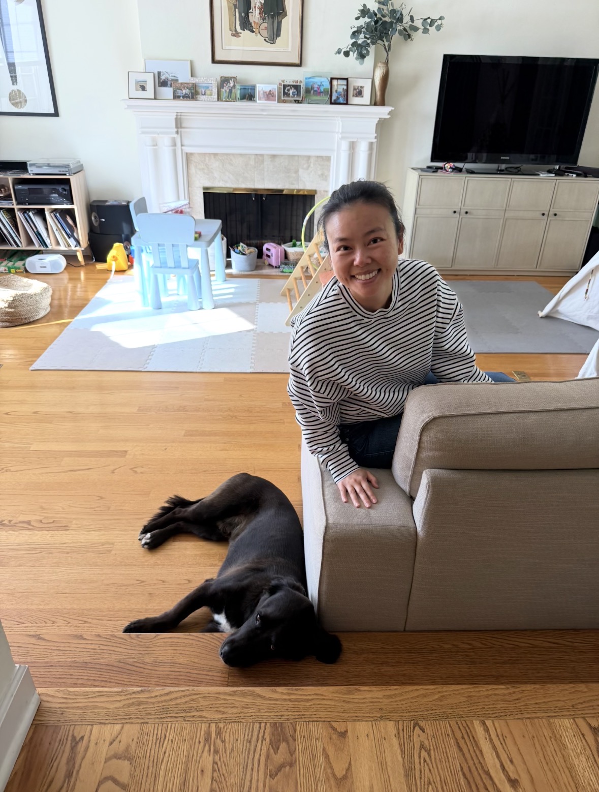 Kuma resting calmly on the floor beside Kei at the family couch